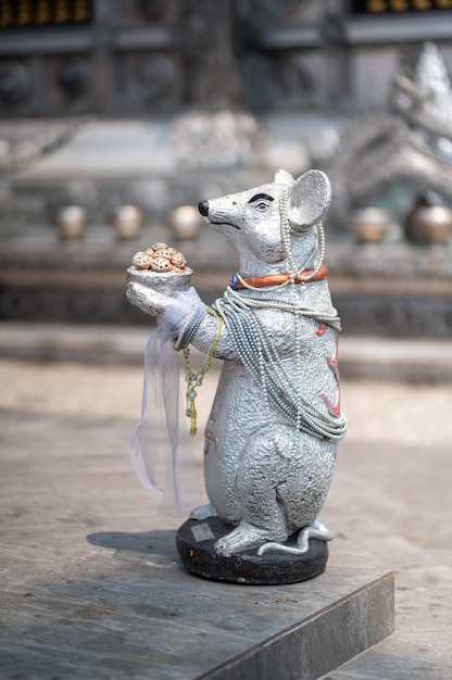 Una estatua de rata sosteniendo un plato de comida.