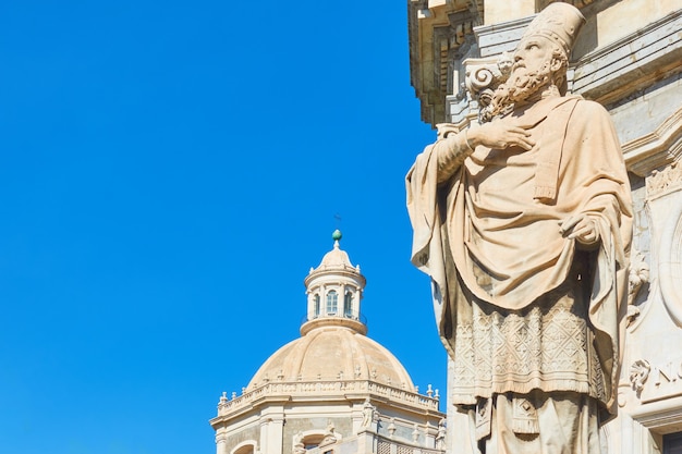 Estatua de Santiago en el frente de la Catedral de Santa Águeda de Catania y el cielo azul, Sicilia, Italia. Composición de copyspace