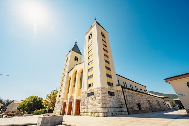 estatua de la Santísima Virgen María sosteniendo una rosa roja mientras la Iglesia de Santiago en Medjugorje