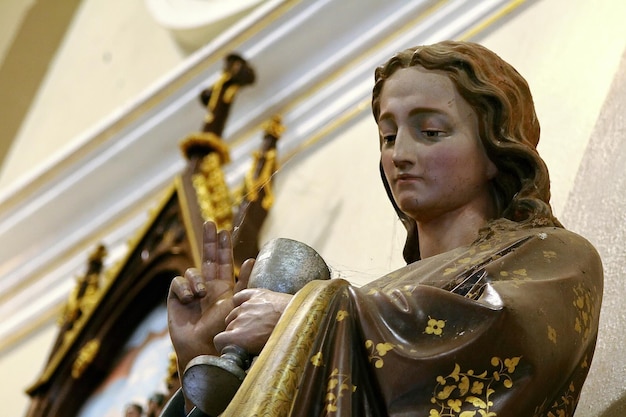 Una estatua de un santo sosteniendo una copa de vino.