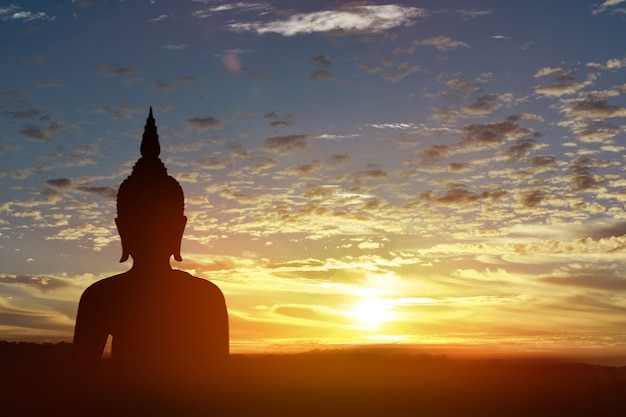 Estatua de silueta de Buda en el fondo del atardecer