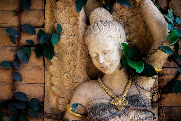 estatua tailandesa de piedra del ángel en un jardín, alto contraste y sobre la luz