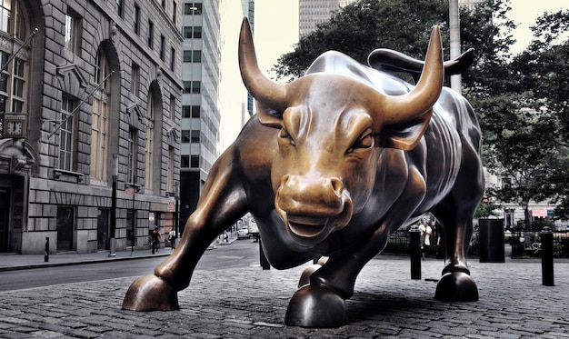 una estatua de toro está en el medio de una calle de la ciudad
