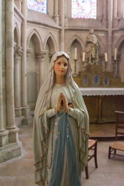 Una estatua de la Virgen María sosteniendo un rosario y rezando