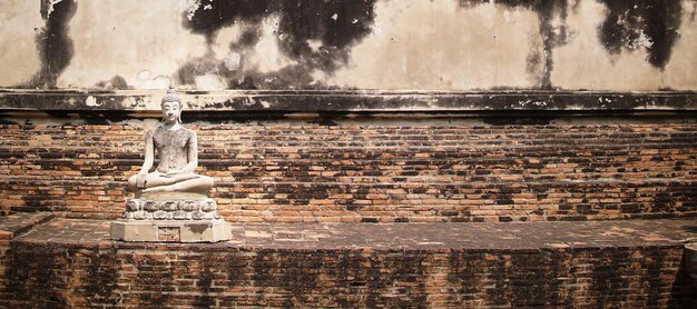 Estátuas antigas de Buda colocadas em paredes de tijolos em templos tailandeses