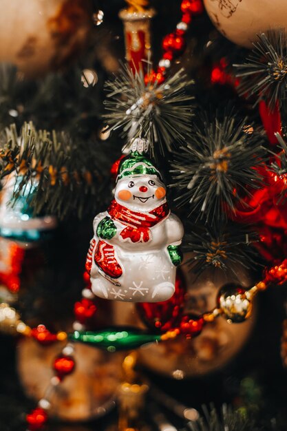 Estatueta de brinquedo de Natal do boneco de neve engraçado pendurada nos galhos da árvore de Natal. Detalhes de ano novo