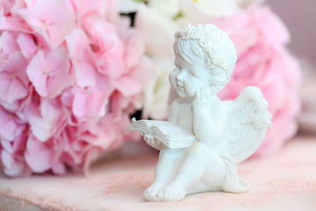 Estatueta de um anjo branco doce em um floral.