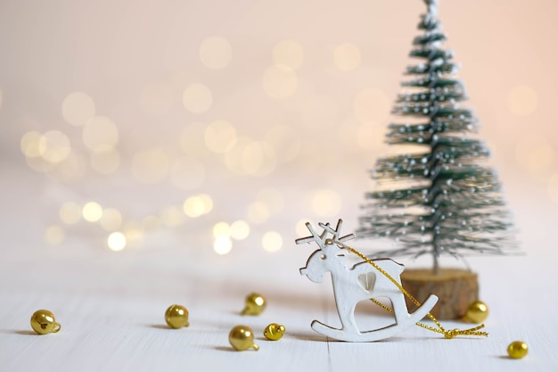 Estatueta de veado, árvore de Natal e bolas douradas em cima da mesa. decorações de Natal