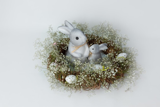 estatuetas Coelhinho da Páscoa e ovos de Páscoa em uma grinalda com flores Ovos coloridos em um ninho e um pequeno