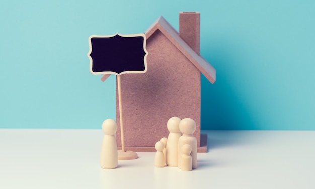 Foto estatuetas de família em madeira, casa modelo. compra de imóveis, conceito de aluguel. mudança para novos apartamentos, copie o espaço