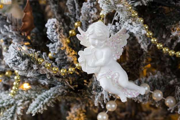 Estatuilla de ángel y cuentas doradas cuelgan de un árbol de Navidad