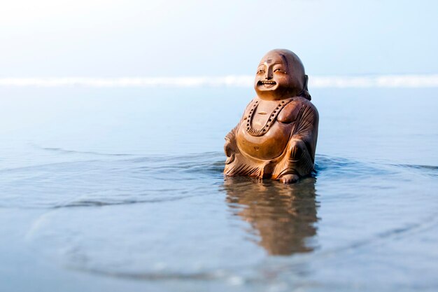 Estatuilla de Buda en la playa Olas azules en el fondo