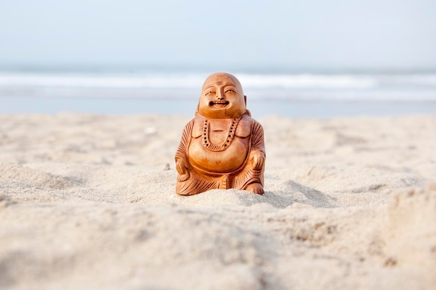 Estatuilla de Buda en la playa Olas azules en el fondo