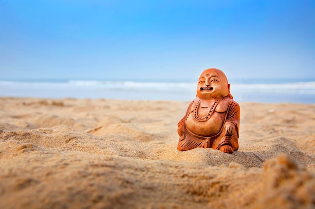 Estatuilla de Buda en la playa Olas azules en el fondo