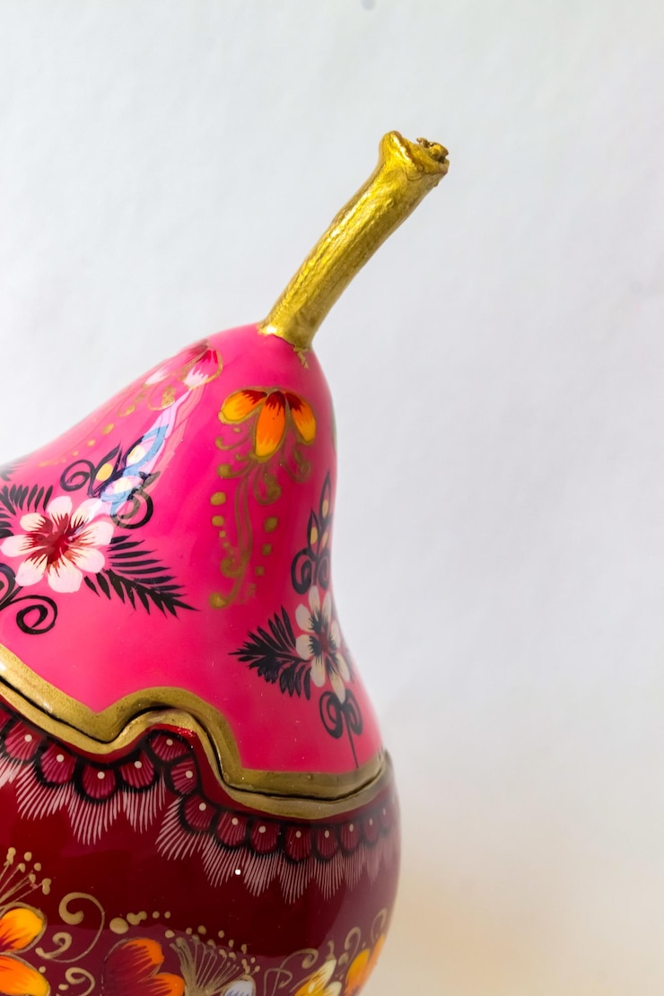 Foto una estatuilla de pájaro rosa y dorado con flores en ella