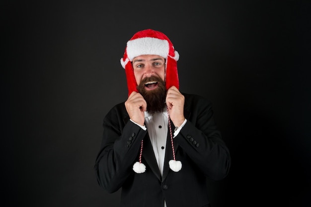 Este chapéu aquece suas orelhas Empresário feliz usa chapéu de Papai Noel Homem barbudo sorri de chapéu com protetores de orelha e peles artificiais Acessório de moda para o Natal Chapéu de caça quente e estiloso para a festa do Papai Noel