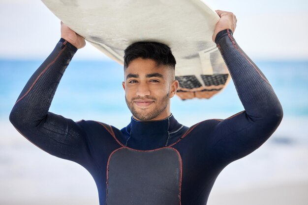 Este é o meu lugar feliz Foto de um jovem segurando uma prancha de surf na praia