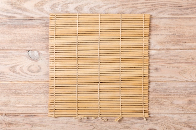Esteira de bambu marrom no fundo de madeira