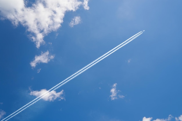 Estela de avión contra el cielo azul cielo con nubes blancas