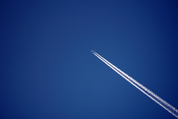 Estelas de avión rastrean estelas químicas en el cielo azul profundo