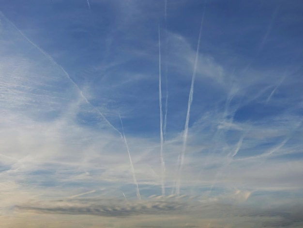 Estelas y líneas de aviones en el cielo nublado azul