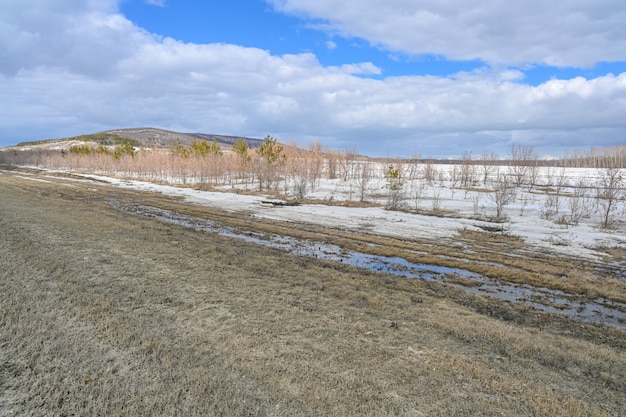 Las estepas, la nieve, los arbustos, la hierba y el cielo nublado. Río Volga. Paisaje de primavera.