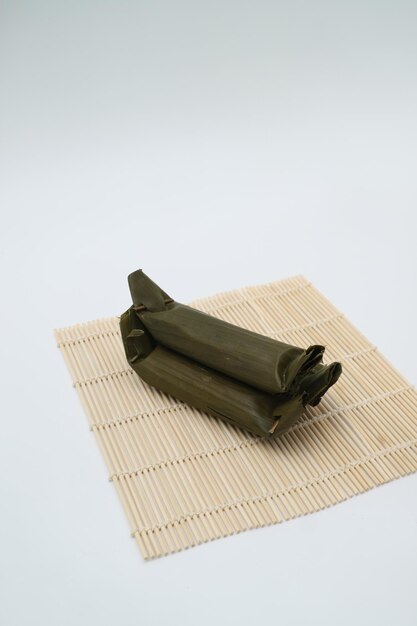 Foto una estera de bambú con una bolsa verde se coloca sobre una pared blanca.