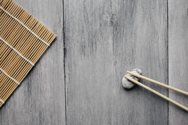 Estera para rollos y palillos para comida asiática china sobre fondo de madera claro plano