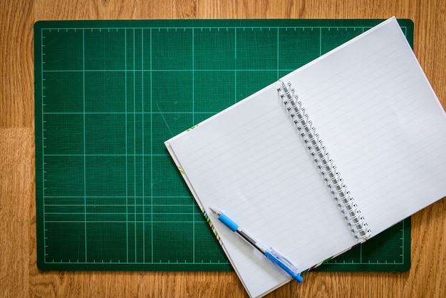 Esteras de corte, cuaderno, pluma sobre el fondo de madera