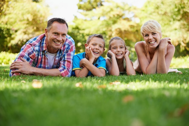 Estes são os momentos que contam na vida Um retrato de vista frontal de uma família feliz deitada na grama ao ar livre