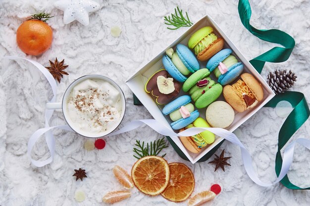 Estética caja de coloridos dulces macarrones regalo para Navidad entre decoraciones de invierno y cacao malvavisco