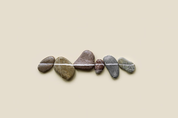 Estética minimal plana colocación de piedras de guijarros marinos con fondo beige de línea blanca Composición de piedra de color natural en el mismo nivel Balance o concepto de armonía filas horizontales de rocas