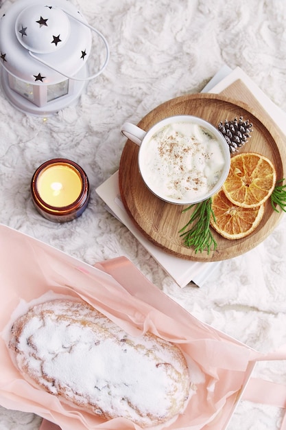 Estética pan tradicional de Navidad stollen con una taza de café, velas y naranjas en una casa acogedora Temporada de vacaciones dulce desayuno de vacaciones