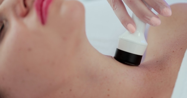La esteticista alisa las arrugas de la zona del rostro y el cuello con la ayuda de un masaje LPG en el salón de belleza. Eliminación de arrugas en rostro y cuello con masaje.