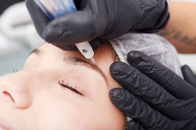 Esteticista aplica maquillaje permanente en las cejas