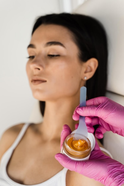 Esteticista aplica máscara facial de levantamiento de oro para estimular los procesos naturales de renovación de la piel y restaurar la elasticidad de la cara