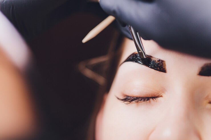 Foto esteticista aplica tinta de hena nas sobrancelhas aparadas em um salão de beleza