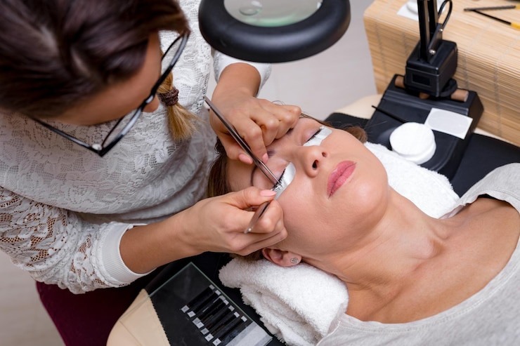 Foto esteticista aplicando cílios estendidos para modelar no salão de beleza.