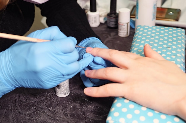 Esteticista aplicando esmalte em unha feminina em um salão de beleza, close-up