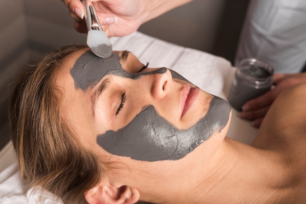 Esteticista aplicando mascarilla en la cara de una mujer joven