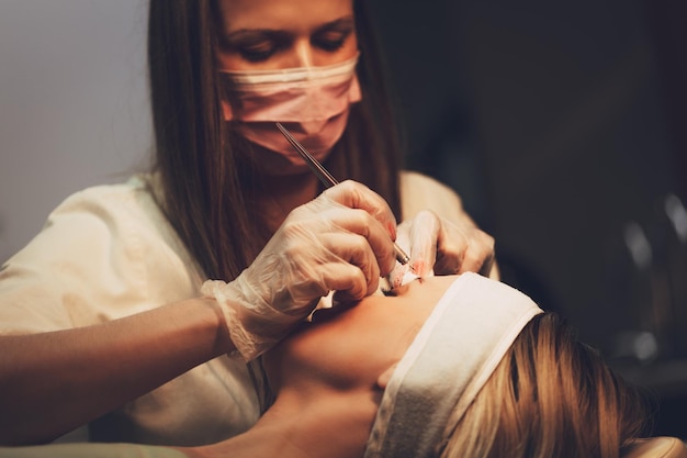 Esteticista aplicando o método japonês de desenho nas sobrancelhas para modelar.