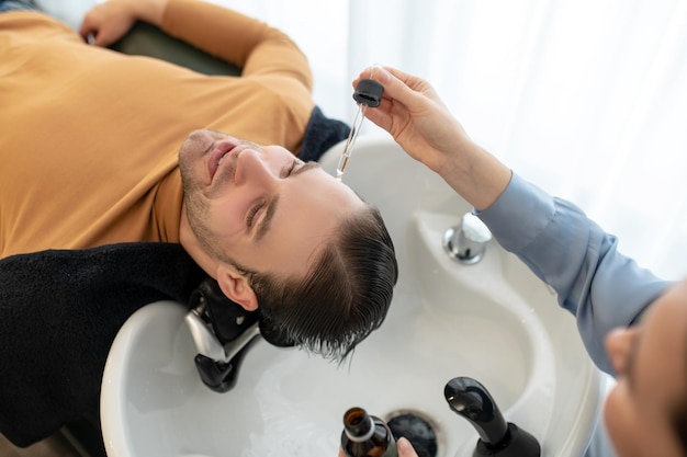 Esteticista aplicando suero capilar en la cabeza del hombre