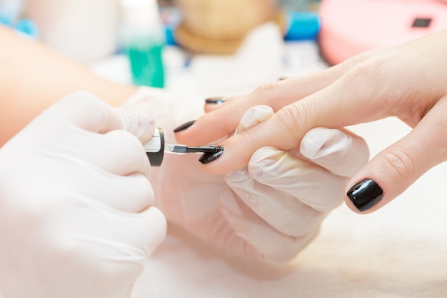 Esteticista aplicando unhas polonês para unhas de mulheres