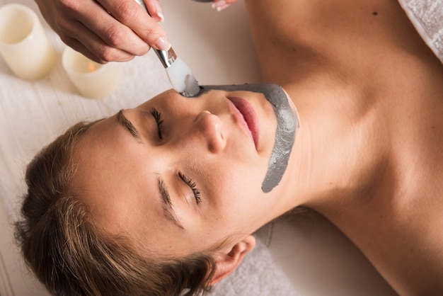 Esteticista aplicar máscara facial no rosto da mulher