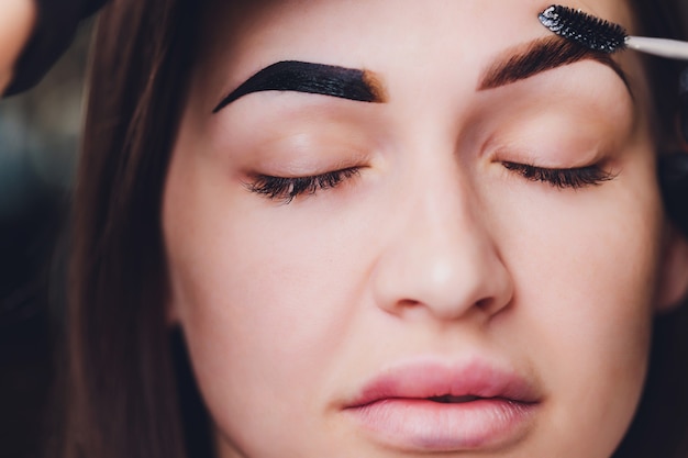 Esteticista cepillando las cejas en un salón de belleza