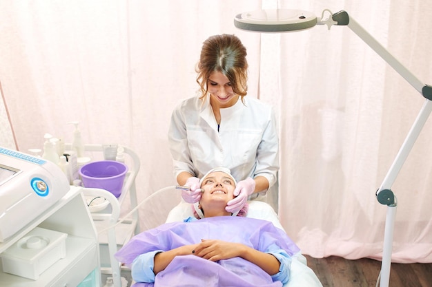 Foto esteticista chica trabaja con pacientes en la oficina.