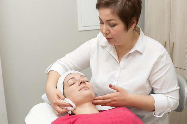 Esteticista para el cuidado de la piel de la cara aplicando una mascarilla de aceite de belleza en la cara con un cepillo en el salón de spa