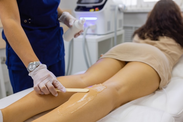 Esteticista, dando tratamento a laser de depilação para mulher na coxa.