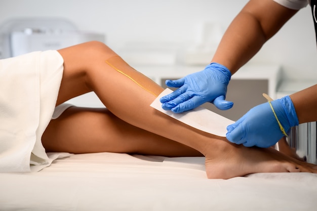 Esteticista depilando pernas femininas em centro de spa