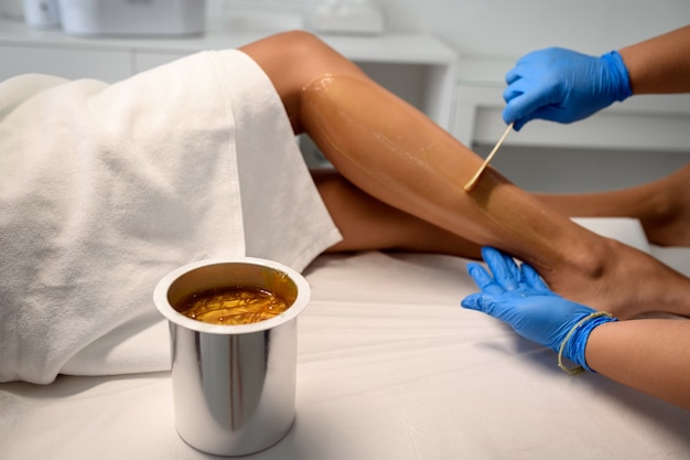 Esteticista depilando pernas femininas em centro de spa